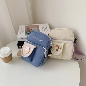Close-up of canvas crossbody bags with cute bear embroidery and adjustable straps