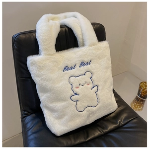 Détail du sac fourre-tout en peluche blanche avec broderie d'ours bleu et texte