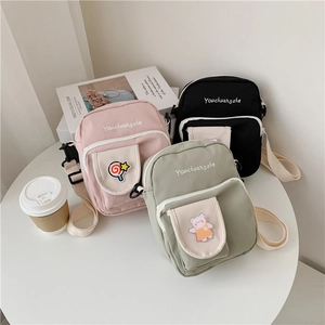 Detailed shot of cute canvas crossbody bags in pink, black and green with bear patches