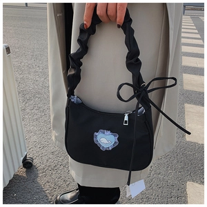 Detail of black pleated hobo bag featuring lace bow and cute whale heart patch
