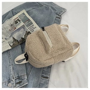 Close-up of soft beige faux shearling mini backpack with cream straps in a cozy setting