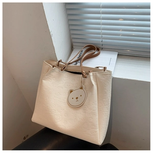Close-up of embossed bear and bow patterns on cream white faux leather tote bag