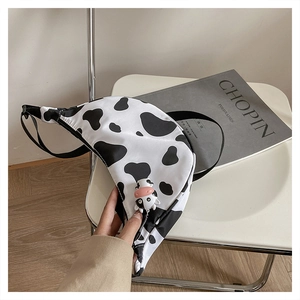 Detail of a nylon cow print crescent bag with a cute cow plush pendant and strap
