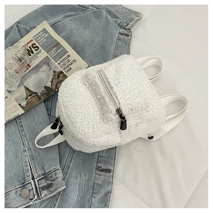 Detailed view of white teddy fur mini backpack on denim jacket for lifestyle display