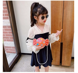 Détail d'un sac enfant en forme de bonbon orange avec pois colorés et chaîne blanche