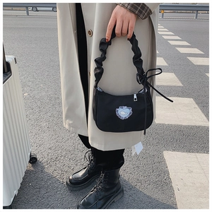 Detail of black crescent handbag with blue heart embroidery and ruffled handle on model