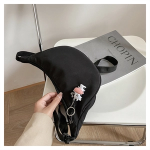 Detail of black nylon crescent crossbody bag with cute cow pendant and zipper closure