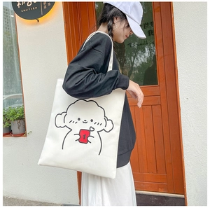Close-up of white canvas tote bag featuring cute cartoon dog print and durable shoulder strap