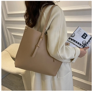 Macro detail of camel leather tote bag with elegant golden buckle on slim shoulder strap