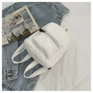 Macro detail of soft white faux lamb wool fabric and metal zipper on mini backpack