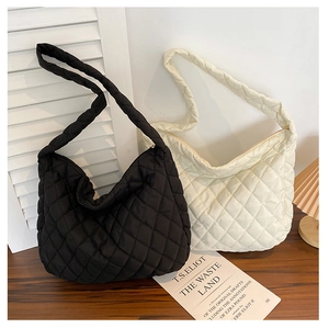 Detailed close-up of quilted puffer tote bags in black and cream on a wooden desk