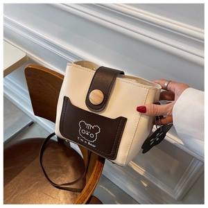 Detail of a two-tone bucket bag with cartoon bear print and a unique wooden button