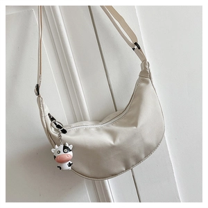 Detail of off-white nylon crescent bag with adjustable strap and cute cow plush charm