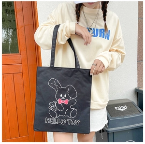 Detail of a large black canvas tote bag featuring a cute cartoon rabbit and hello toy text