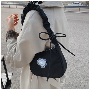 Detail of black cloud pleated shoulder bag featuring a blue heart lace patch and bow strap