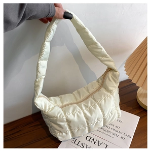 Detail view of white quilted puffer shoulder bag with glossy finish and zipper closure