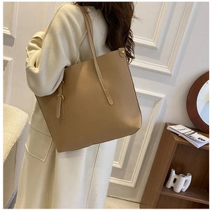 Detailed view of khaki leather tote bag featuring long handles and side metal buckle detail