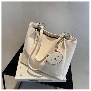 Close-up of cream embossed tote bag with cartoon bear patterns and gold hardware details