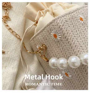 Detail of lace bucket bag with daisy embroidery, pearl handle, and gold metal hooks