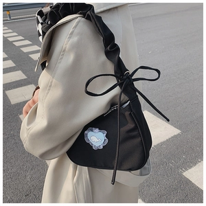 Detail of black crossbody bag with ruffled strap, bow accent, and whale embroidery patch