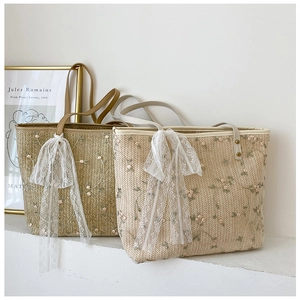 Detail of straw tote bags featuring floral embroidery and large white lace bows
