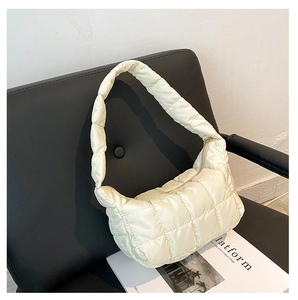 Close-up of cream-white quilted dumpling bag with soft padded texture on a chair
