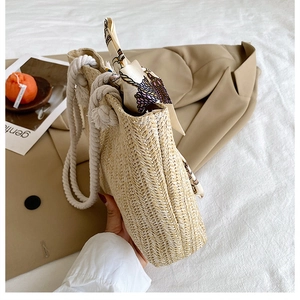 Detail of a straw tote bag featuring thick white cotton handles and a printed silk scarf