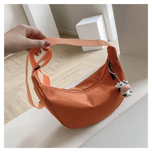 Orange nylon half-moon crossbody bag detail with cute cow charm and adjustable strap