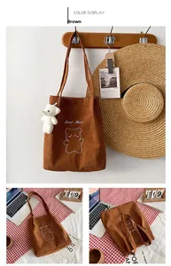 Dettaglio borsa tote in velluto a coste marrone con ricamo orso e ciondolo di peluche