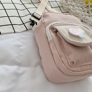Pink canvas crossbody bag for women with decorative patches and adjustable strap