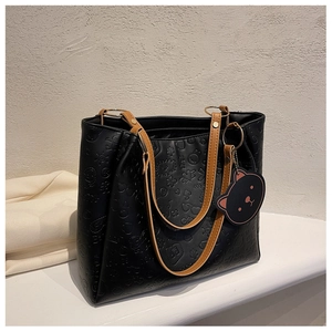 Detail of black leather tote bag featuring cartoon embossing and a bear head tag