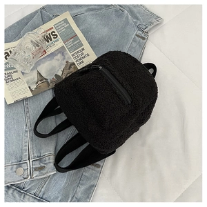 Close-up of fluffy black fleece mini backpack with front pocket in a lifestyle setting