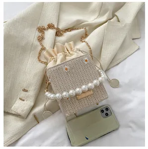 Detail of tweed bucket bag featuring daisy embroidery, pearl handle, and golden chain