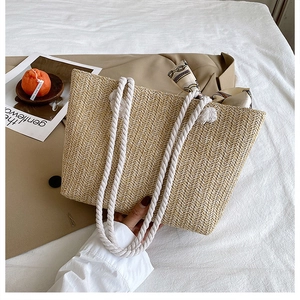 Close-up of beige straw tote bag featuring rope handles and decorative floral silk scarf