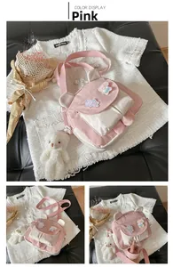 Detailed view of pink cartoon bear ears crossbody bag with plush charm and strap