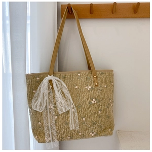 Detail of straw woven tote bag with pink floral embroidery and lace ribbon bow
