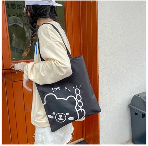 Close-up of black canvas tote bag featuring a cute white bear and Japanese text