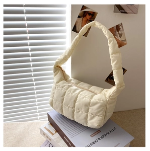 Close-up of cream white quilted nylon shoulder bag with golden zipper and square pattern