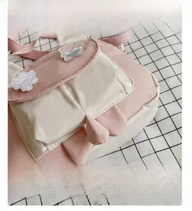 Detail of cute pink and white crossbody bag with cartoon badge and animal ears decoration