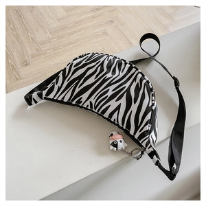 Close-up of zebra print nylon crossbody bag featuring a cute cow plush pendant detail