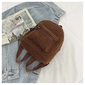 Detail of a mini brown faux shearling backpack with front pocket and zipper detail