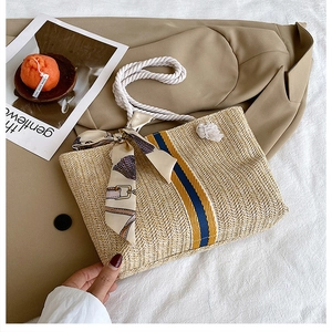 Detail of straw woven tote bag featuring beige herringbone pattern and blue-yellow stripes
