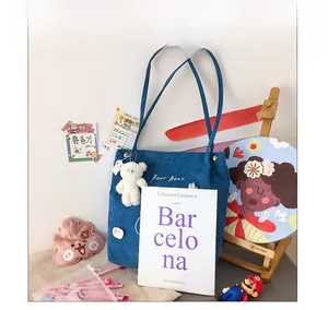Close-up of navy blue corduroy tote bag with Bear Boar embroidery and plush bear charm