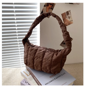Detail of coffee brown quilted nylon moon bag with pleated handle and gold zipper closure