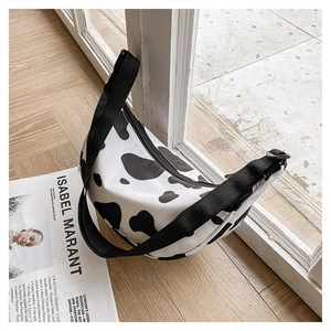 Detail view of a cow print nylon crescent bag on a wooden floor in natural light