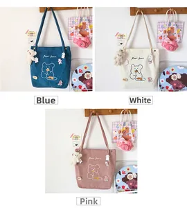 Detailed close-up of corduroy tote bags with bear embroidery in blue, white and pink