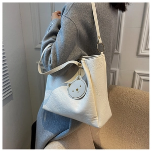 Detail of white embossed tote bag with cartoon pattern and a cute bear charm accessory