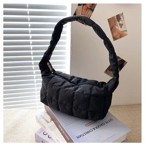 Detail of black quilted nylon shoulder bag with gold zipper on art books