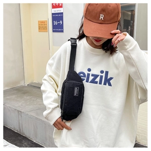 Street style shot of a black corduroy chest bag with Fashion Instinct woven label detail