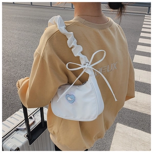 Details der weißen Plissee-Schultertasche mit Schleife und Herz-Stickerei-Aufnäher
